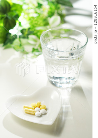 錠剤とカプセルの薬とグラスに入ったミネラルウォーター 129916154