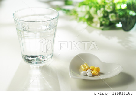 錠剤とカプセルの薬とグラスに入ったミネラルウォーター 129916166