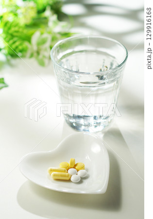 錠剤とカプセルの薬とグラスに入ったミネラルウォーター 129916168