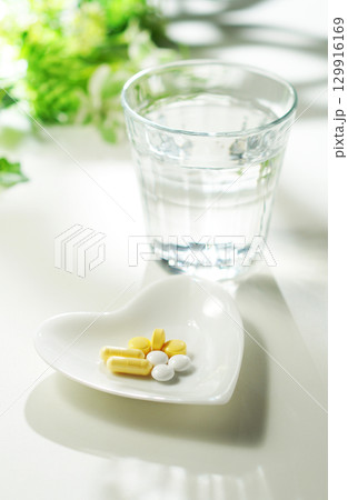 錠剤とカプセルの薬とグラスに入ったミネラルウォーター 129916169