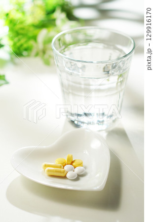 錠剤とカプセルの薬とグラスに入ったミネラルウォーター 129916170