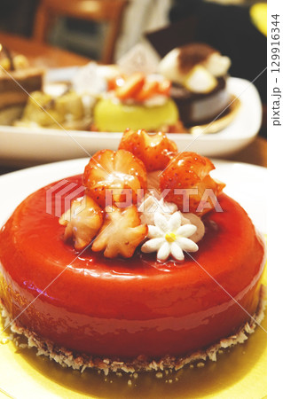 お皿に並べられたイチゴのホールケーキとショートケーキやタルトの洋菓子 お皿に並べられたイチゴのホールケーキとショートケーキやタルトの洋菓子 129916344