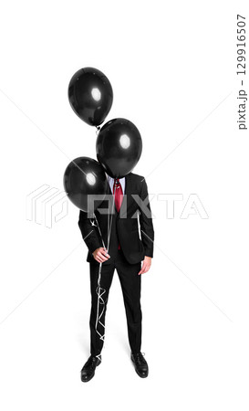 Businessman in suit hidden behind black balloons with playful emotion 129916507