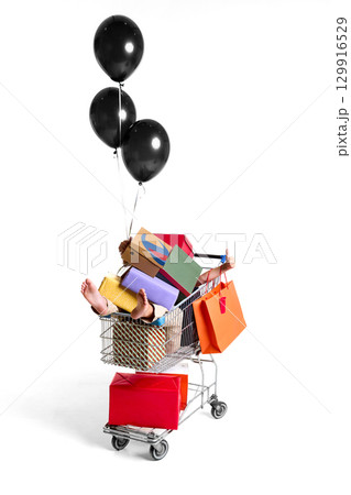 Shopping cart filled with colorful gift boxes and balloons on white background Shopping cart filled with colorful gift boxes and balloons on white background 129916529