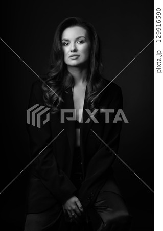Beautiful woman with dark suit and wavy hair studio portrait 129916590