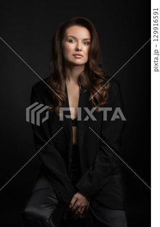 Beautiful woman with dark suit and wavy hair studio portrait Beautiful woman with dark suit and wavy hair studio portrait 129916591