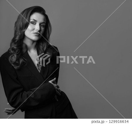 Woman with long wavy hair and black suit studio portrait 129916634