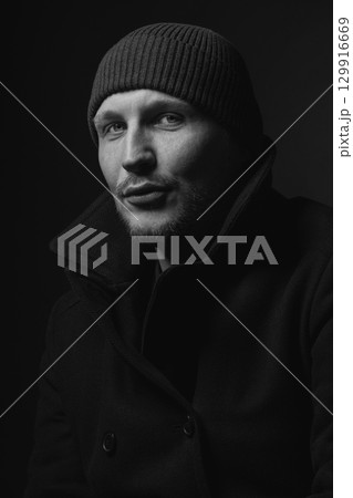 Serious man with black winter coat and winter hat studio portrait 129916669