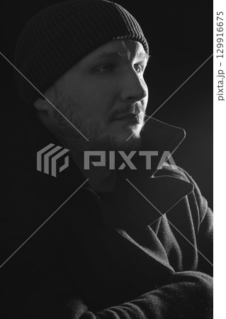 Serious man with black winter coat and winter hat studio portrait 129916675