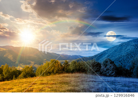 mountain landscape with forest on the hill on autumn equinox. day and night time change concept. beautiful view in to the rural valley. alpine countryside scenery with sun and moon at twilight 129916846