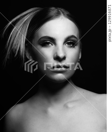Beautiful woman portrait with classic hairstyle and nude make-up in black background Beautiful woman portrait with classic hairstyle and nude make-up in black background 129916871