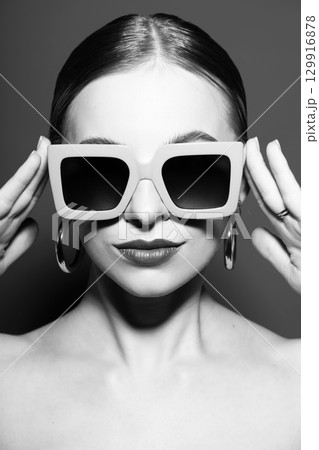 Woman portrait with classic hairstyle, big retro sunglasses and round earrings 129916878