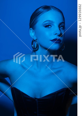 Abstract beautiful woman studio portrait with classic hairstyle, corset and round golden earrings 129916882