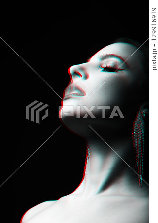 Woman studio portrait with fancy earrings blowing smoke through mouth in RGB color split effect style 129916919