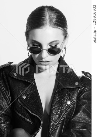 Woman studio portrait with black punk leather jacket, sunglasses and without bra Woman studio portrait with black punk leather jacket, sunglasses and without bra 129916932