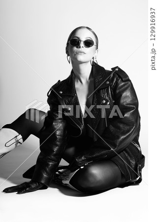 Woman studio portrait with black punk leather jacket, sunglasses and without bra Woman studio portrait with black punk leather jacket, sunglasses and without bra 129916937