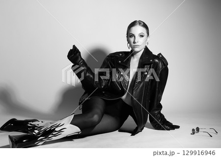 Woman black and white studio portrait with black punk leather jacket and without bra Woman black and white studio portrait with black punk leather jacket and without bra 129916946
