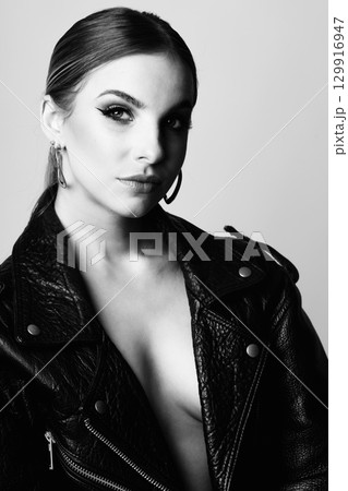 Woman black and white studio portrait with black punk leather jacket and without bra Woman black and white studio portrait with black punk leather jacket and without bra 129916947