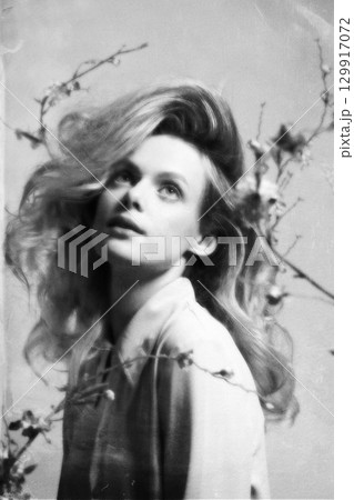 Beautiful woman with big wavy hair and flowers studio portrait in retro vintage style 129917072