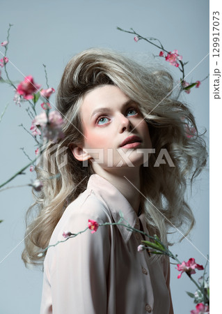 Beautiful woman with big wavy hair and flowers studio portrait 129917073