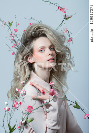 Beautiful woman with big wavy hair and flowers studio portrait 129917075
