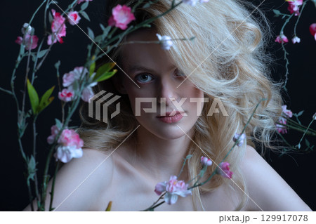 Beautiful woman with big wavy hair and flowers studio portrait 129917078