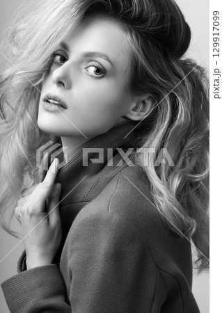 Beautiful woman with big wavy hair and garment coat studio portrait Beautiful woman with big wavy hair and garment coat studio portrait 129917099