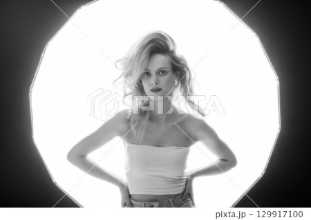 Beautiful woman with big wavy hair black and white studio portrait in bright illuminated soft box background 129917100