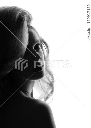 Beautiful woman with big wavy hair black and white studio portrait in bright background 129917120