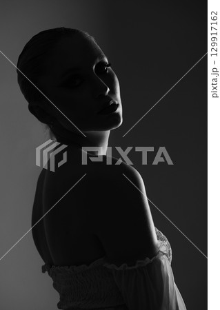 Beautiful woman dark silhouette studio portrait on gray background Beautiful woman dark silhouette studio portrait on gray background 129917162