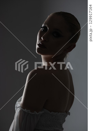 Beautiful woman dark silhouette studio portrait on gray background 129917164