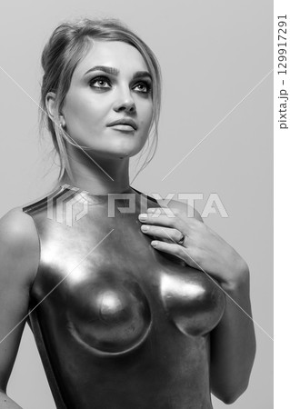 Studio portrait of beautiful woman with metallic corset looking aside the camera with seductive look Studio portrait of beautiful woman with metallic corset looking aside the camera with seductive look 129917291