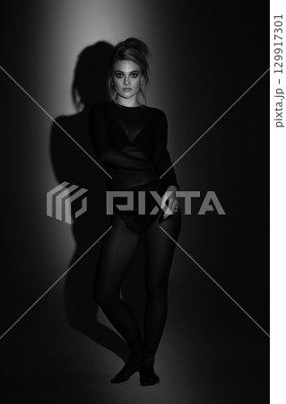 Beautiful woman with tight black clothes black and white studio background Beautiful woman with tight black clothes black and white studio background 129917301