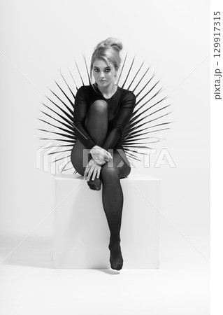 Black and white portrait of beautiful woman with tight black clothes sitting on white cube Black and white portrait of beautiful woman with tight black clothes sitting on white cube 129917315