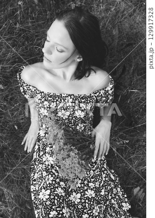 Woman in Floral Dress Resting on Grass 129917328