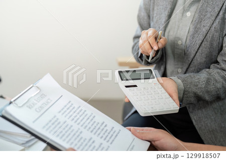 Real Estate Agent Using Calculator for Property Financing Real Estate Agent Using Calculator for Property Financing 129918507