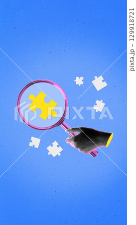 Digital artwork of hand with magnifying glass focusing puzzle piece on blue background 129918721