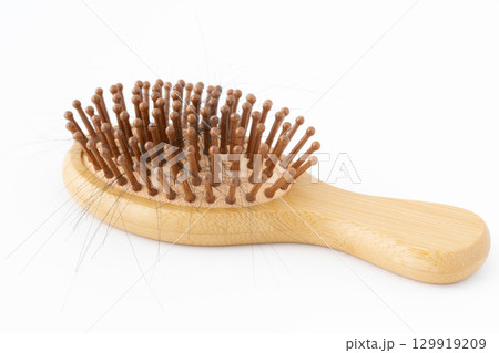 白背景に髪の毛のついた竹製のヘアブラシ 129919209