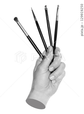 Woman hand holds black cosmetics brushes, isolated on transparent background, cosmetics and visage concept. Contemporary art Woman hand holds black cosmetics brushes, isolated on transparent background, cosmetics and visage concept. Contemporary art 129919250