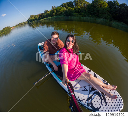 Couple Paddleboarding on a Serene Lake Couple Paddleboarding on a Serene Lake 129919392