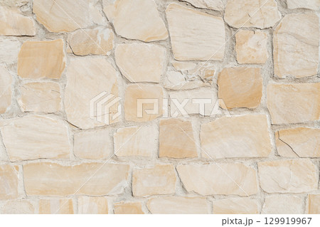 Antique ancient stone wall masonry texture background. Old wall made of beige stone blocks  129919967