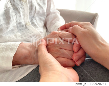 シニア女性の手を握る女性の手のクローズアップ 129920234