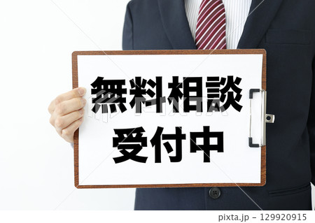 ビジネスマンが掲げる無料相談受付中の紙を挟んだバインダー 129920915