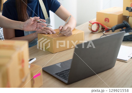 Entrepreneur collaborating on logistics with packages and laptop Entrepreneur collaborating on logistics with packages and laptop 129921558