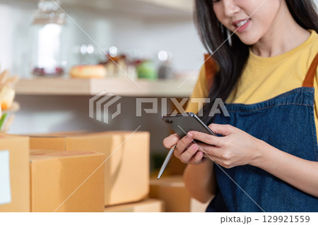 Entrepreneur engaging with smartphone while managing packages Entrepreneur engaging with smartphone while managing packages 129921559