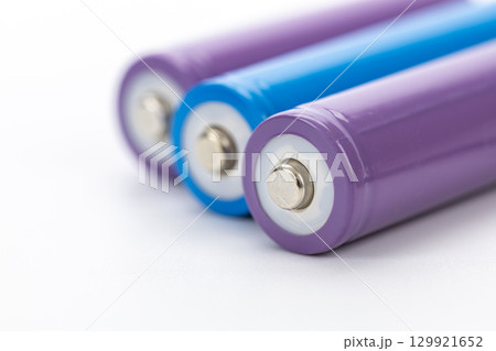 Colorful batteries closeup view cylindrical shape metallic terminal purple and blue energy storage clean background technology power supply macro detail 129921652