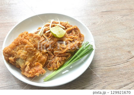 Pad Thai stir fried rice noodles with dry shrimp and egg topping crispy fried chicken on plate  129921670