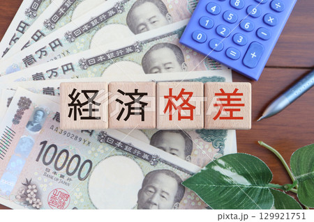 経済格差を象徴する1万円札と赤文字の日本語ブロック	 129921751