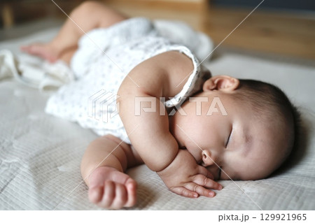 指しゃぶりをしながら昼寝する生後5ヶ月の赤ちゃん	 129921965