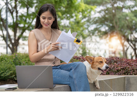 Remote Work and Pet Companionship. Woman reviewing documents with her corgi dog beside her. 129922316